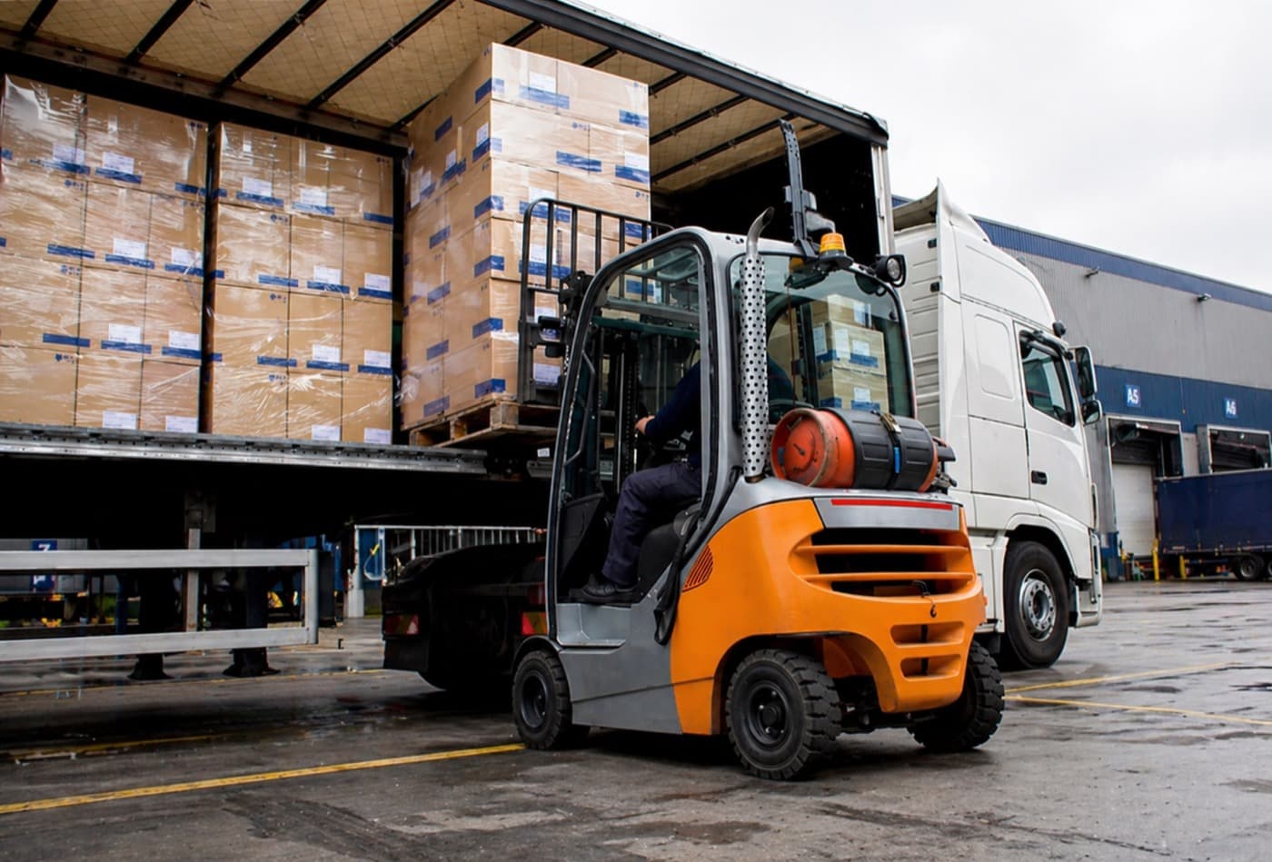 Forklift unloading a palletised semi-trailer at a warehouse loading dock